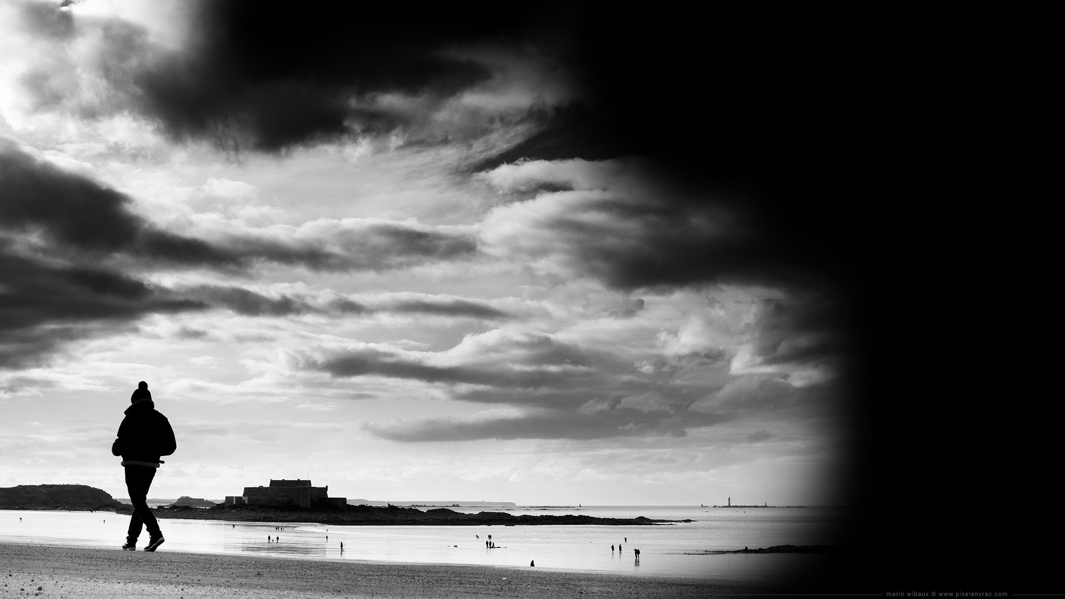 Photo de Bretagne en noir et blanc : Saint-Malo : marcheur sous les nuages de la plage du Sillon : fond d'écran